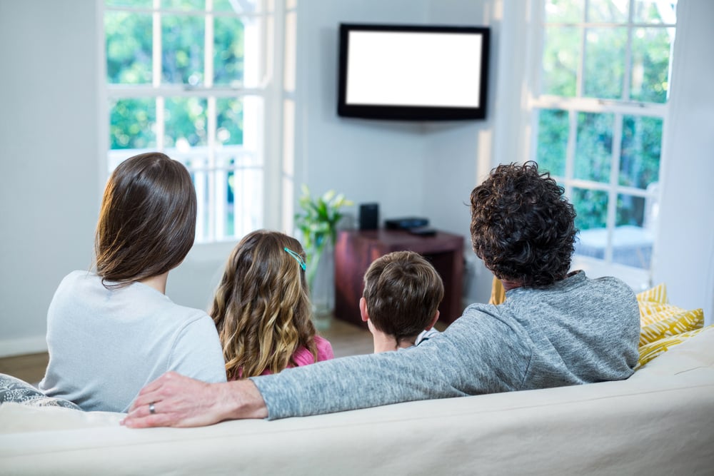 Family watching television while sitting on sofa at home-1